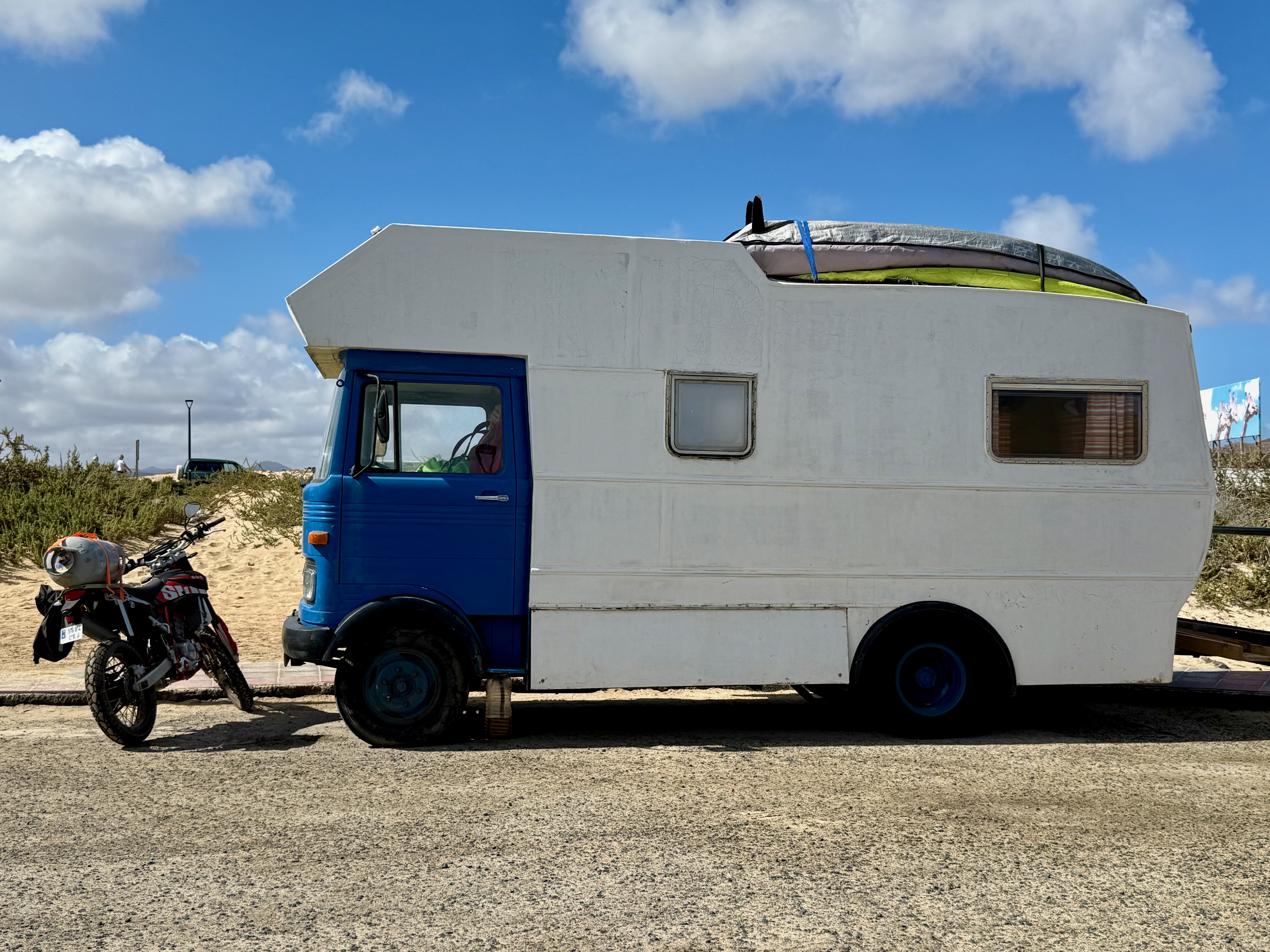 Blue-and-white camper van with surfboards on the roof
